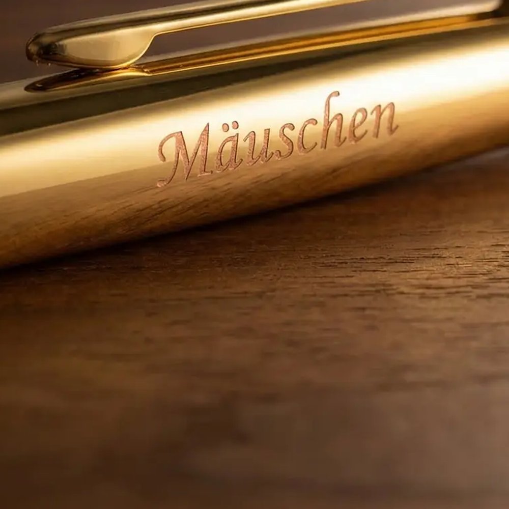Nahaufnahme der Schreibschrift-Gravur Mäuschen auf der goldenen Kappe eines Hörner Legno Kugelschreibers