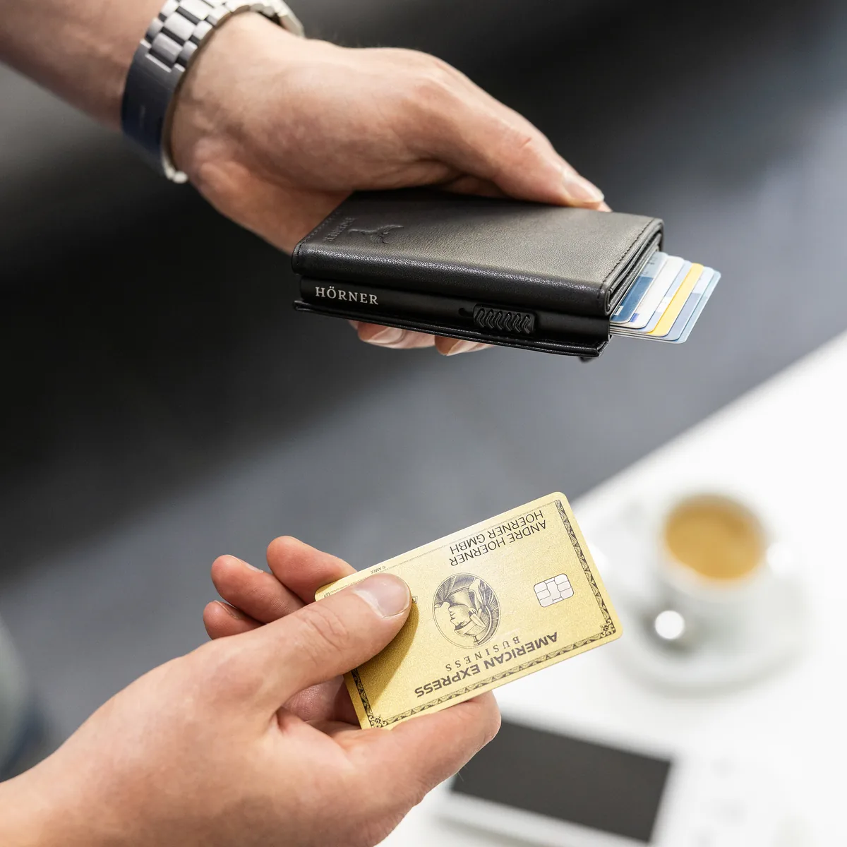 Gros plan du Slim Wallet Hörner Nexus : une main retire une carte du compartiment Pop-Up déployé en escalier
